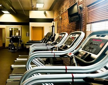 A row of treadmills beside the brick wall.