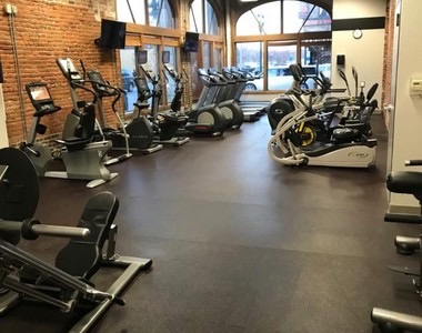 Cardio machines lined up along the arched front windows.